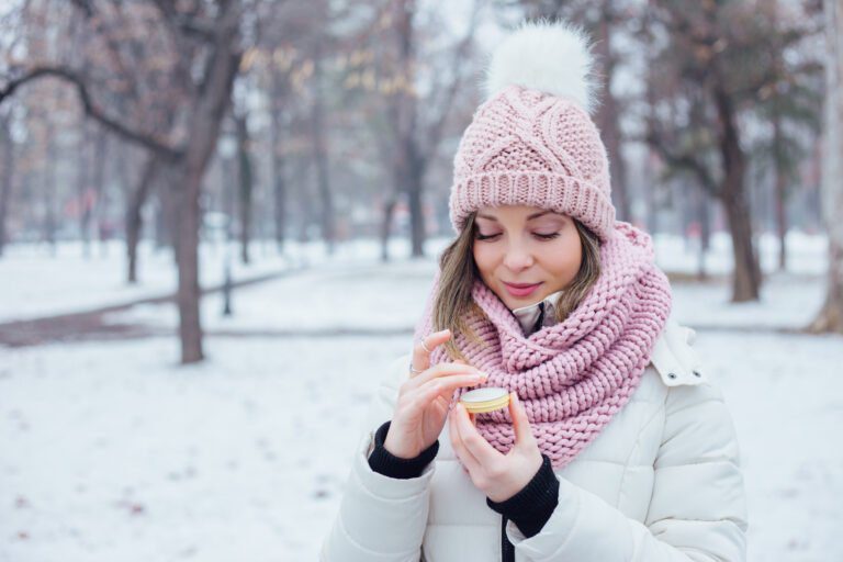 Young women apply lip care balm outside, on cold weather
